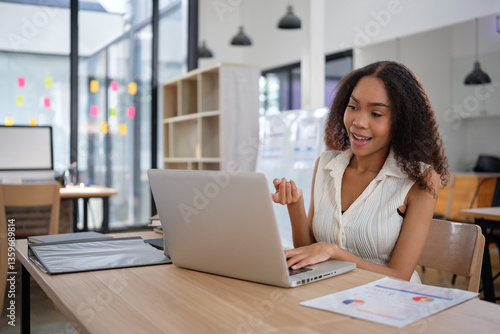 Free Download Confident young businesswoman actively participates in a video conference call from her modern office. - GFXLoad