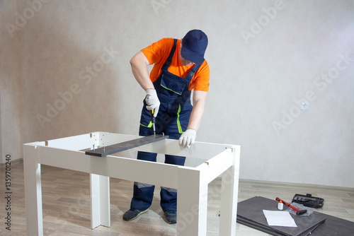 A middle-aged man in overalls collects furniture from various parts in a close-up in a bright room