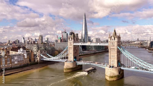 Boat passing under the Tower Bridge, London, Great britain, passing clouds, and the city skyline in the background