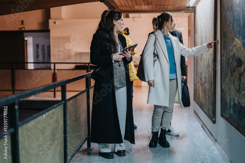People discussing and analyzing artwork on display in a museum environment. The scene portrays collaboration, culture, and the appreciation of art during a professional visit or research excursion.