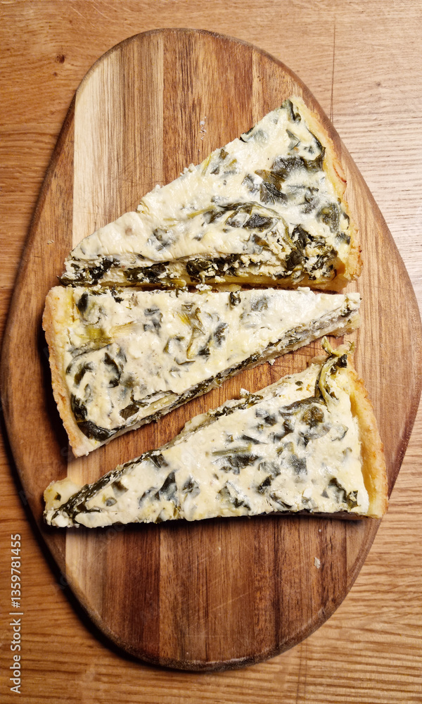 Fototapeta premium A top-down shot of triangular slices of Swiss chard and cottage cheese pie arranged on a wooden cutting board