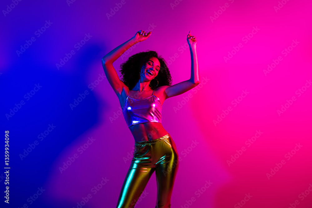 Young woman dancing joyfully in glowing neon lights wearing stylish metallic outfit, displaying vibrant energy Young woman dancing joyfully in glowing neon lights wearing stylish metallic outfit, displaying vibrant energy