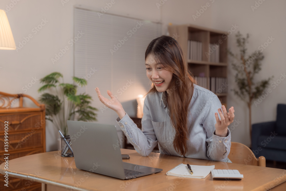Young Asian businesswoman using laptop computer making video call and gesturing while working from home at night with a positive attitude and a smile on her face Young Asian businesswoman using laptop computer making video call and gesturing while working from home at night with a positive attitude and a smile on her face