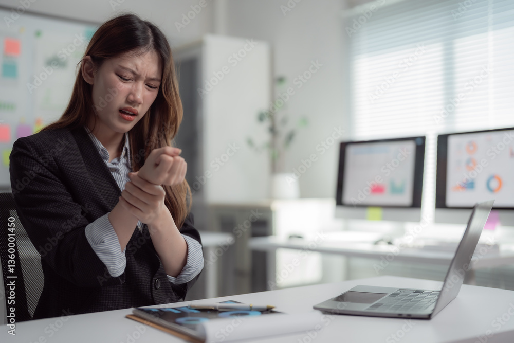 Young Asian manager suffering wrist pain from using laptop computer for a long time, carpal tunnel syndrome, office syndrome, health care concept Young Asian manager suffering wrist pain from using laptop computer for a long time, carpal tunnel syndrome, office syndrome, health care concept