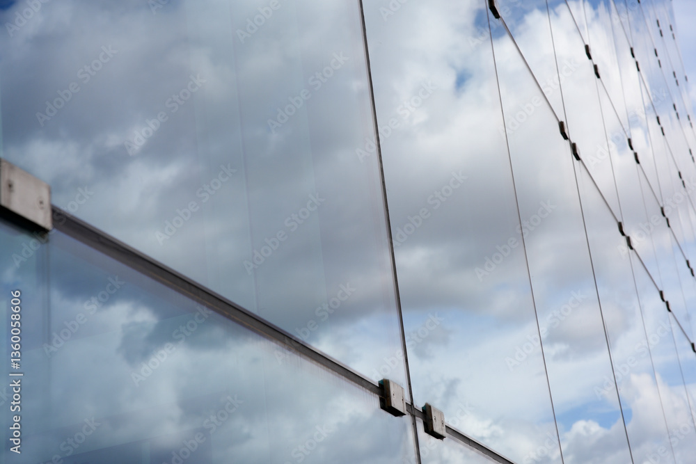 Fototapeta premium Modern glass building reflecting clouds in windows