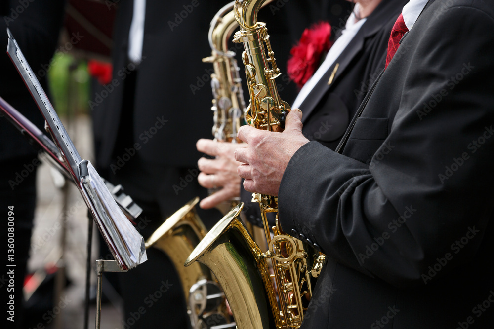 Obraz premium Musicians playing saxophones at a street festival in a vibrant outdoor setting during the evening