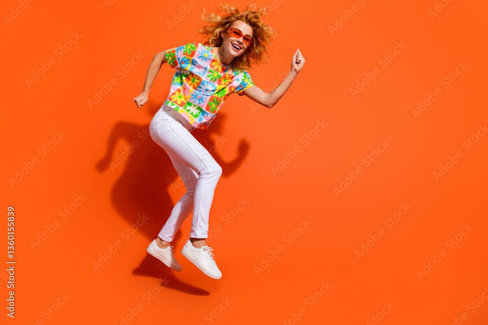 Portrait of a young woman jumping joyfully in colorful attire on an orange background, expressing happiness Portrait of a young woman jumping joyfully in colorful attire on an orange background, expressing happiness