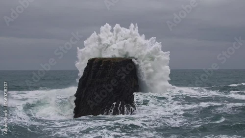 Powerful ocean waves crashing against sea stack amidst stormy weather