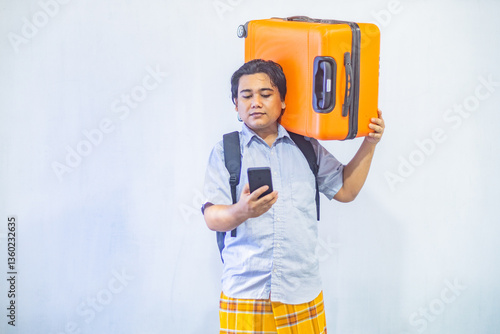 Obraz na płótnie Portrait Asian muslim man carrying suitcase while holding mobile phone with copy space inside. Concept Going home for Eid Mubarak. Isolated image on white background w salonie