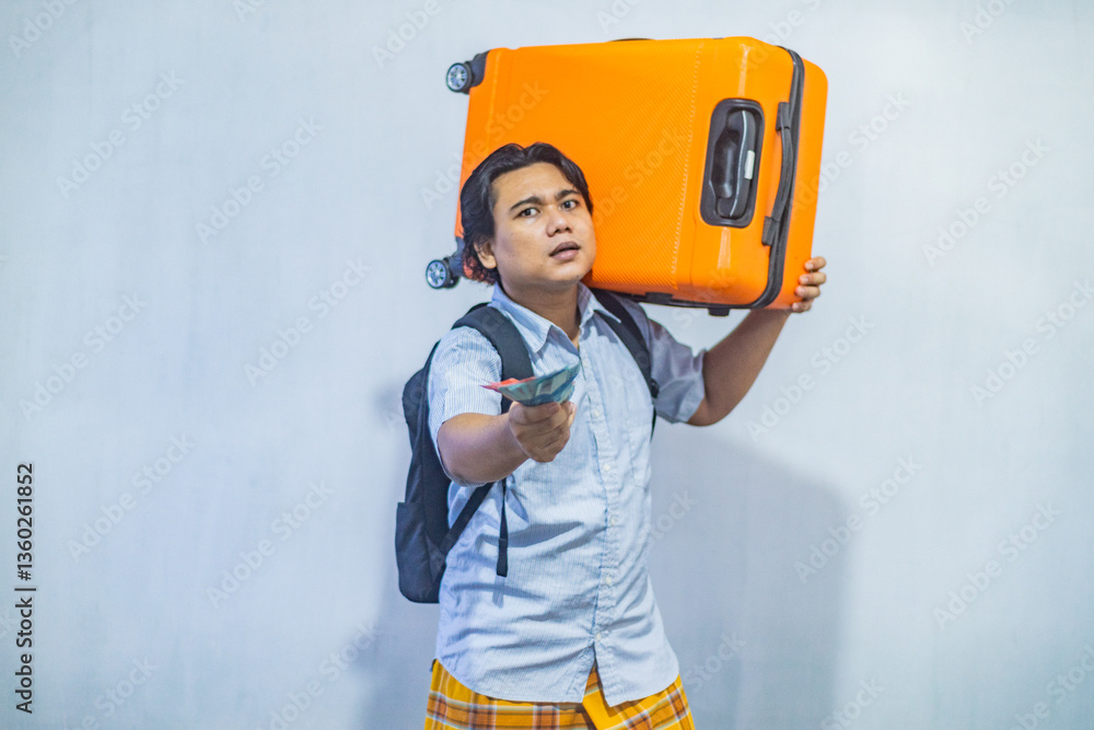 Portrait Asian muslim man carrying suitcase while holding money to be distributed during Eid Al-Fitr (THR). Concept Going home for Eid Mubarak. Isolated image on white background