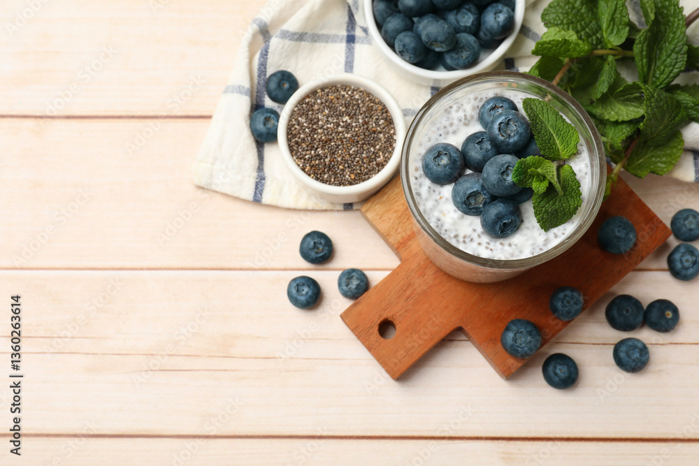 Delicious chia pudding with blueberries and mint in glass on wooden table, flat lay. Space for text Delicious chia pudding with blueberries and mint in glass on wooden table, flat lay. Space for text