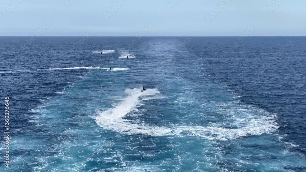 Tourists on a summer vacation enjoying their time in the middle of the wide blue sea as they happily drive jet skis during a bright sunny day, aerial view slowly zooming out Video Tourists on a summer vacation enjoying their time in the middle of the wide blue sea as they happily drive jet skis during a bright sunny day, aerial view slowly zooming out Video