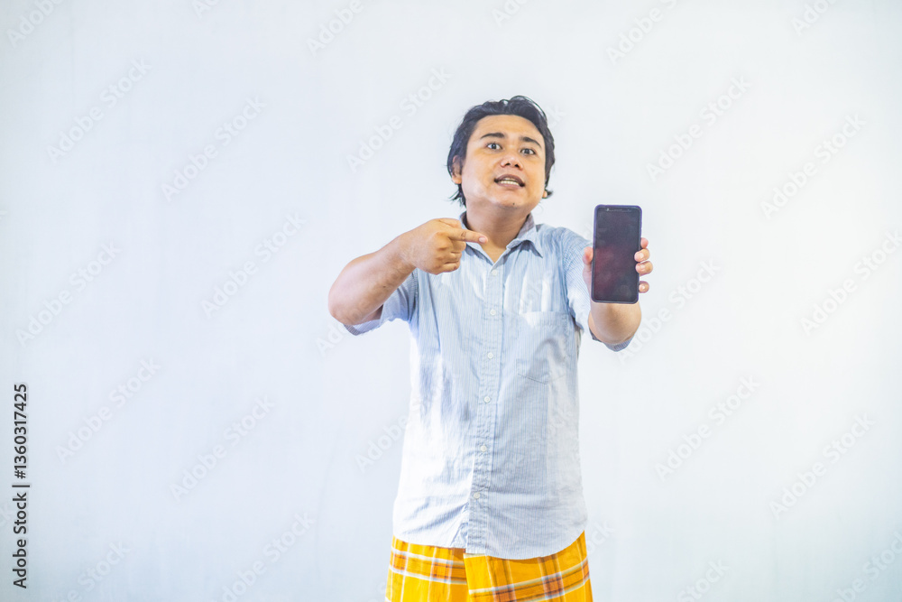 Portrait of surprised young Asian Muslim men showing blank screen on phone with copy space inside. Ramadan and Eid Mubarak concept