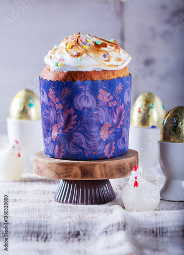 Easter cake, chocolate eggs in gold foil and chicken-shaped candles on a light background.