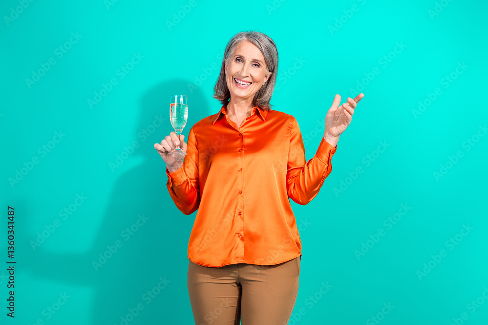 Portrait of a Confident Mature Woman in Vibrant Orange Blouse Holding a Champagne Glass Against a Bright Turquoise Background Portrait of a Confident Mature Woman in Vibrant Orange Blouse Holding a Champagne Glass Against a Bright Turquoise Background