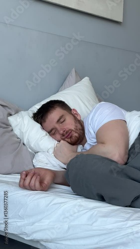 Young man is sleeping well in bed in bedroom in the morning