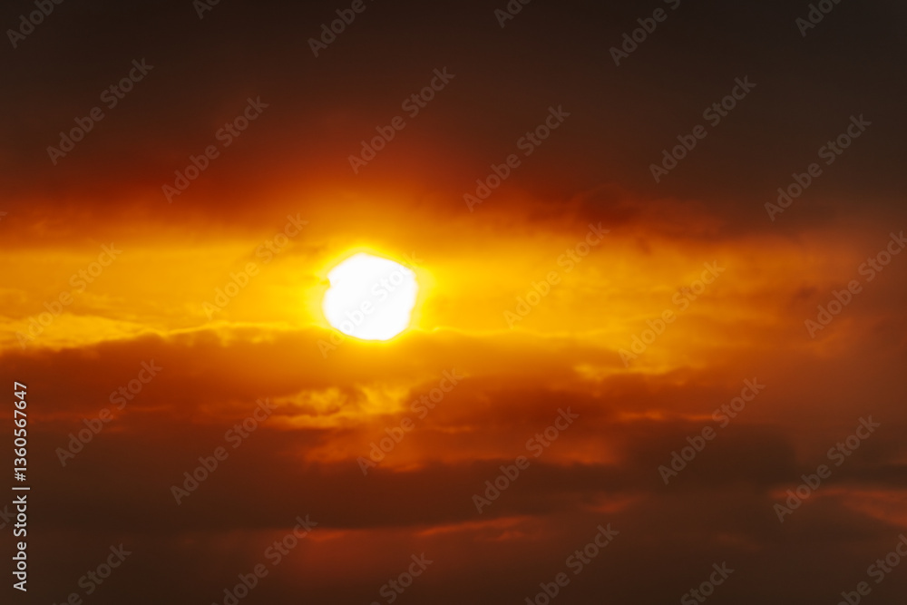 Obraz premium A partial solar eclipse glows through dramatic red-orange clouds, casting an intense and surreal light in a dark sky. Includes ample copy space.