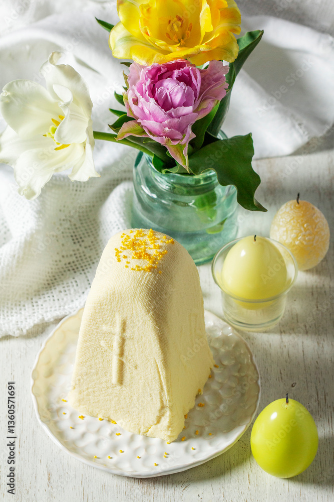 Traditional Slavic Easter dish made from cottage cheese - Paskha, a bouquet of tulips and candles on a light background.