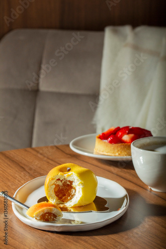 Obraz na płótnie Mousse cake with peach filling covered with velvet glaze and a cup of latte on a table in a cafe. w salonie