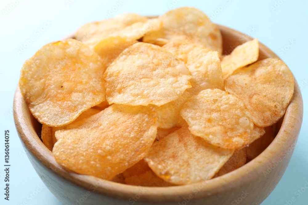 Tasty potato chips in bowl on light blue background, closeup Tasty potato chips in bowl on light blue background, closeup