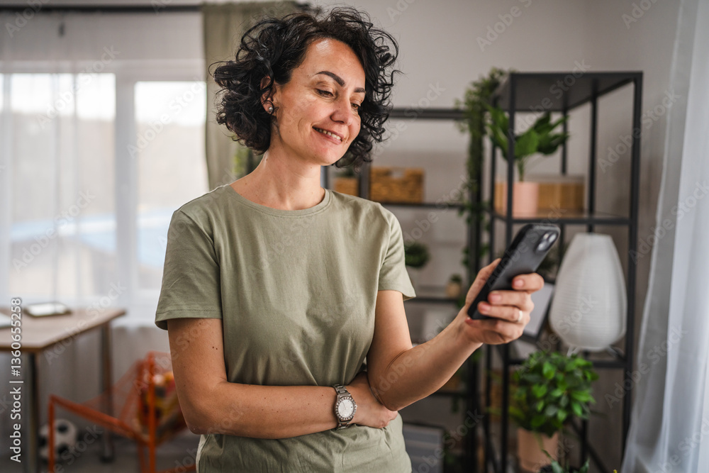 curly hair woman use mobile phone while stand in the living room curly hair woman use mobile phone while stand in the living room