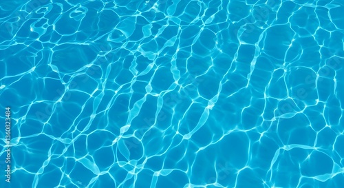 A top-down shot showing a close-up texture of clear blue water in a swimming pool or similar body of water. The sunlight creates a pattern of light and shadow on the water's surface.