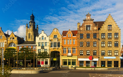 Scenic view of summer cityscape of Roeselare overlooking belfry of Saint Michael Church rising above typical Flemish style townhouses on central Grote Markt square on sunny day, West Flanders, Belgium
