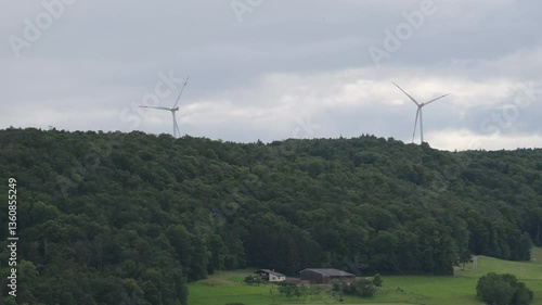 Wind turbines in a green landscape under a cloudy sky in the countryside during late afternoon