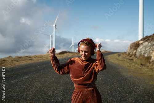 Young sporty woman dancing and listening to music in a wind farm