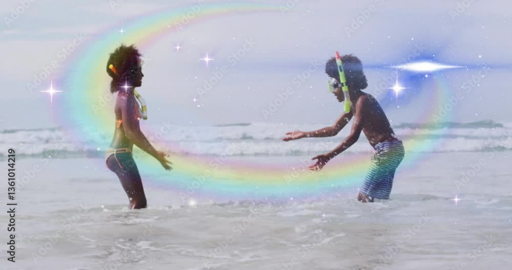 Children playing in ocean waves with rainbow and sparkles animation overlay Children playing in ocean waves with rainbow and sparkles animation overlay