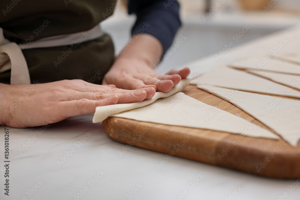 Obraz premium Woman rolling croissant from fresh dough at light table indoors, closeup