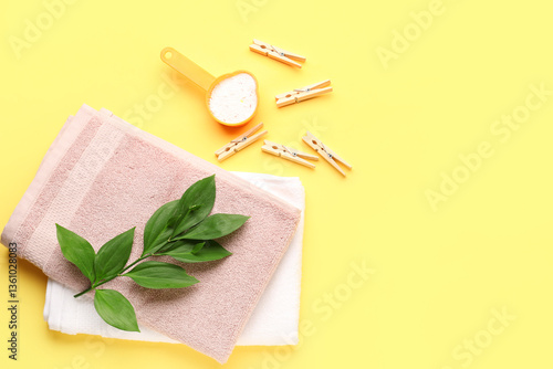 Laundry detergent, clothespins, towel and plant branch on yellow background