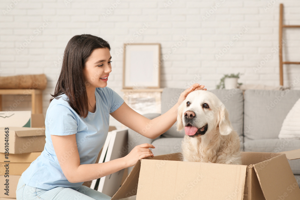 Fototapeta premium Young happy woman and cute Labrador dog with boxes on moving day sitting at home