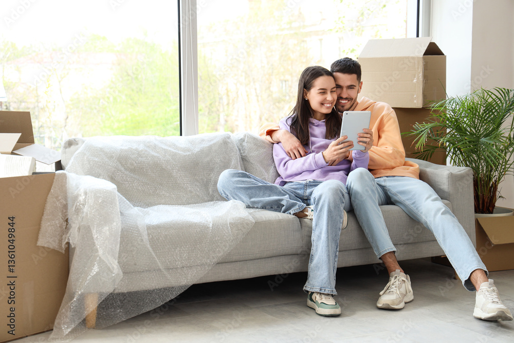 Fototapeta premium Young couple using tablet computer in room on moving day