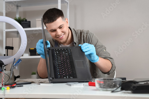 Φωτογραφία Male technician repairing laptop at table in service center