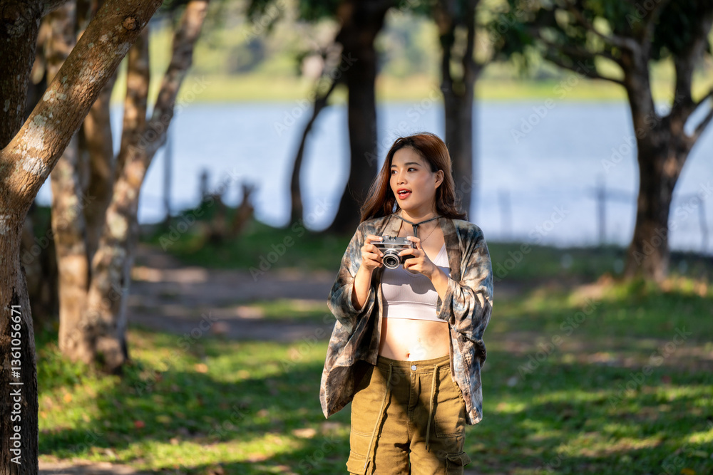 A woman is walking in a park with a camera in her hand A woman is walking in a park with a camera in her hand