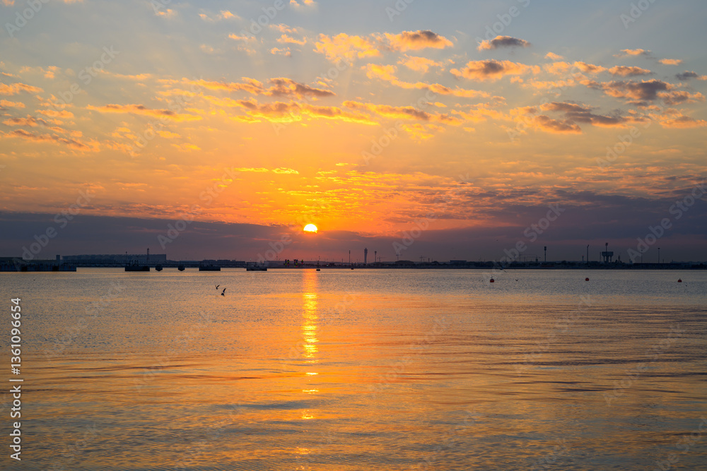 Naklejka premium Doha Qatar: Sunrise over the water View from the old Doha port, creating a beautiful orange and pink sky