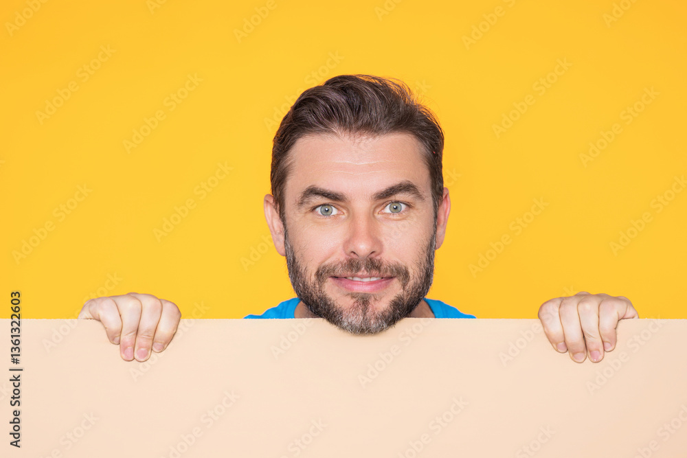 Handsome happy man holding empty board on studio. Smiling guy showing blank signboard with copyspace. Idea and offer. Your advertisement. Blank advertising board with empty space for text, mockup.