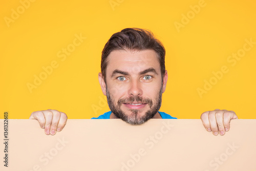Obraz na płótnie Handsome happy man holding empty board on studio. Smiling guy showing blank signboard with copyspace. Idea and offer. Your advertisement. Blank advertising board with empty space for text, mockup. w salonie