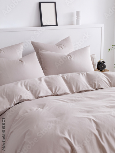 Double bed with fluffy duvet in a beige duvet cover and four pillows close-up side view vertical photo