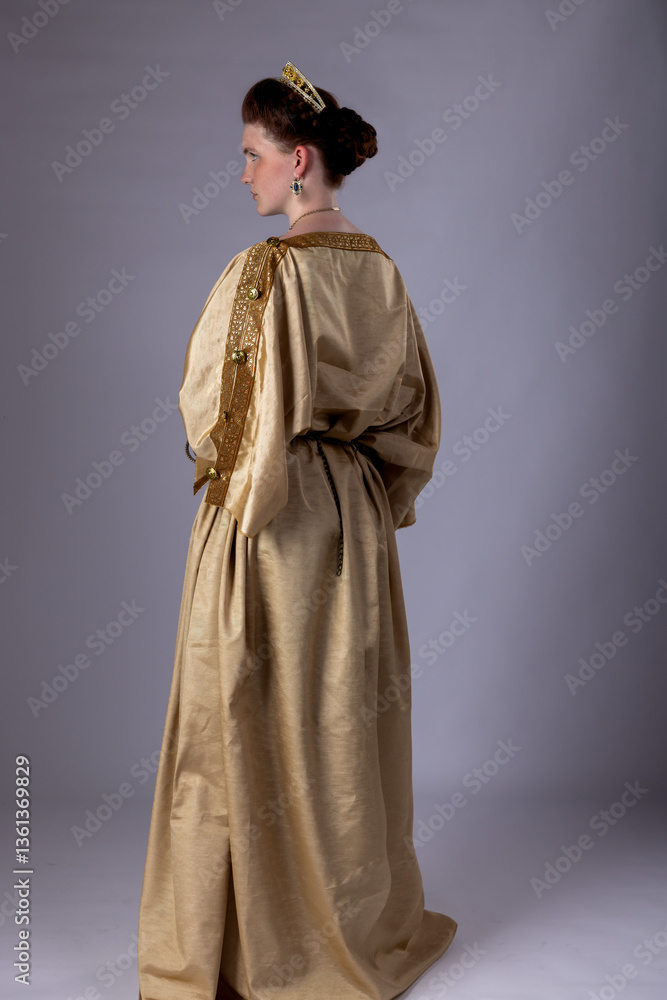 Naklejka premium Young Roman woman wearing a tunic stands against a studio backdrop