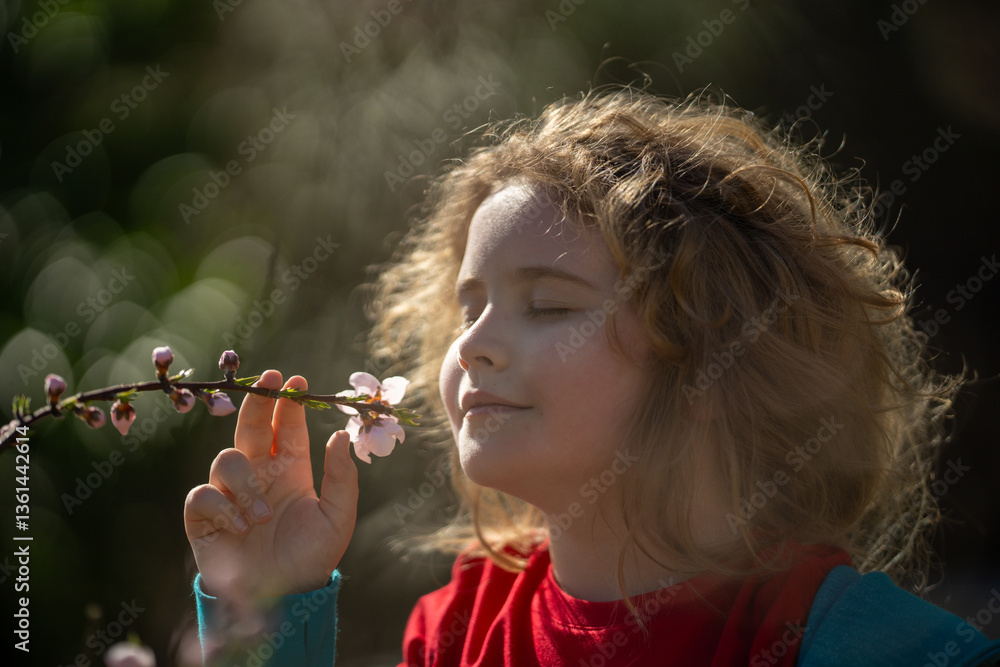 Child face close-up in spring park. Child enjoying spring sunshine. Child smelling flowers spring sunny day. Portrait of kid in blossoming garden. Child fun in spring. Kid with pink blossom flowers.