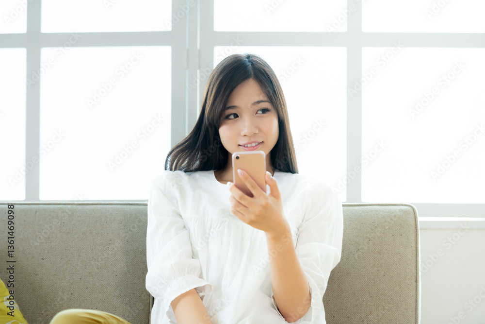 リビングでスマホを操作する若い女性