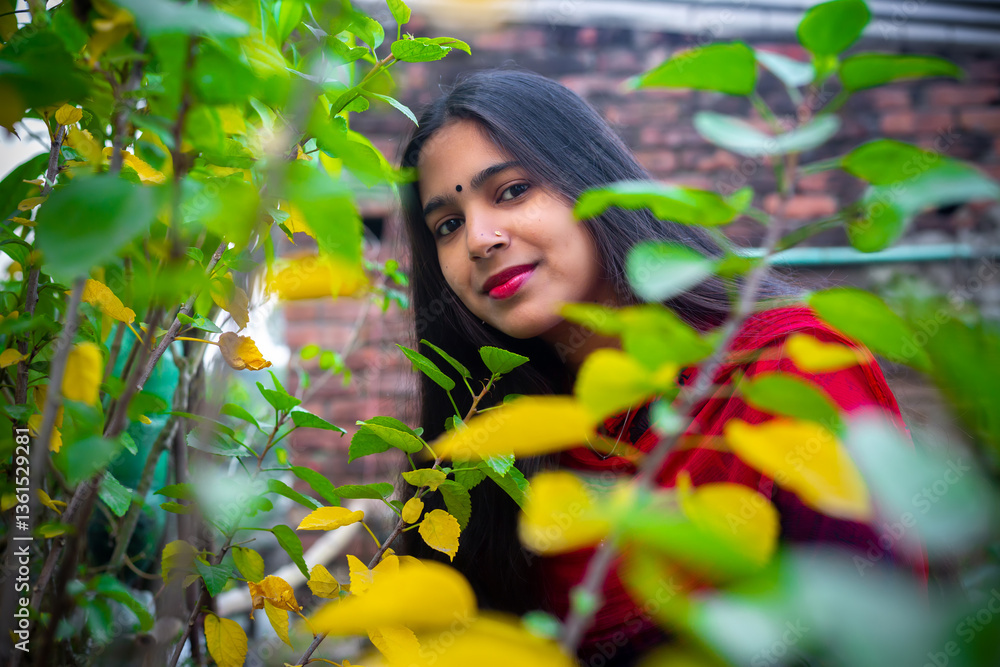 A beautiful young woman is looking through the green and yellow leaves of spring. Fashion model portrait. A beautiful young woman is looking through the green and yellow leaves of spring. Fashion model portrait.