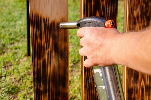 Treating wooden planks with fire from a gas cylinder.