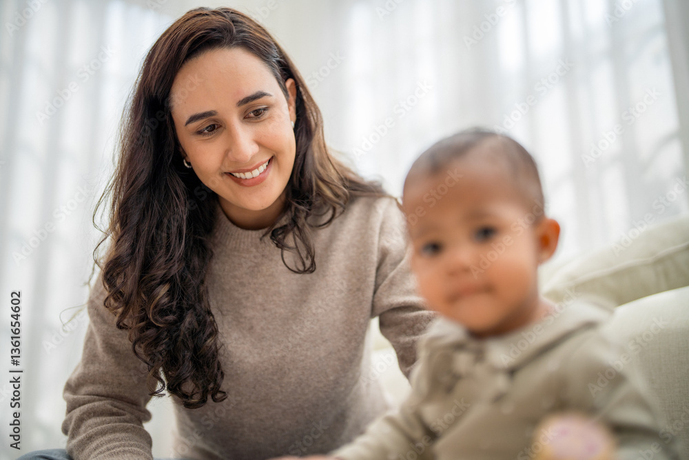 Smiling woman interacting with her toddler in a cozy living room setting during daytime Smiling woman interacting with her toddler in a cozy living room setting during daytime