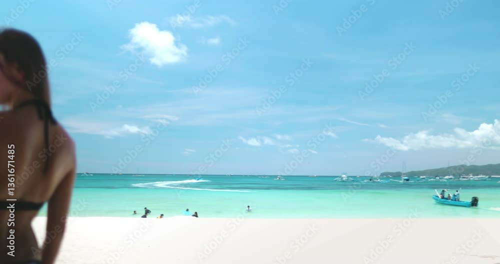 Young woman is taking a break from swimming and enjoying the shade of a palm tree on a beautiful white sand beach in the tropics Young woman is taking a break from swimming and enjoying the shade of a palm tree on a beautiful white sand beach in the tropics