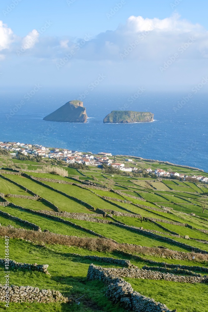 Agricultural fields divided by stone walls, with the village of Feteira and the Goat Islands in the background, on the island of Terceira, Azores, Portugal.