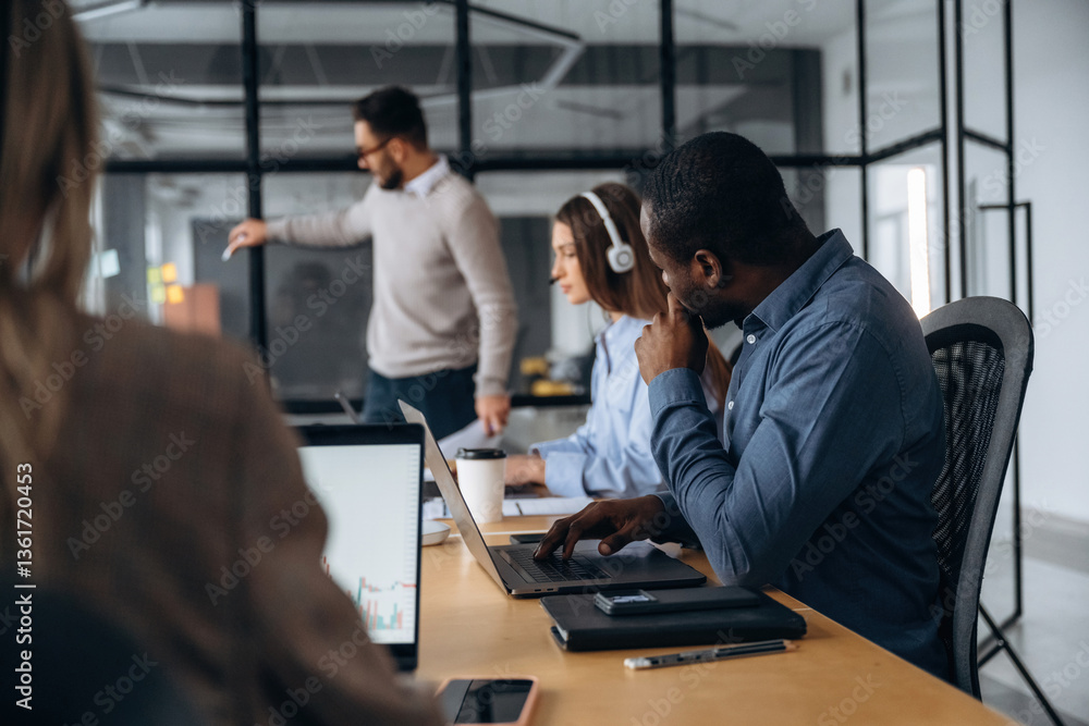 Wireless devices, laptops on the table. Professional workers are in the modern office together Wireless devices, laptops on the table. Professional workers are in the modern office together