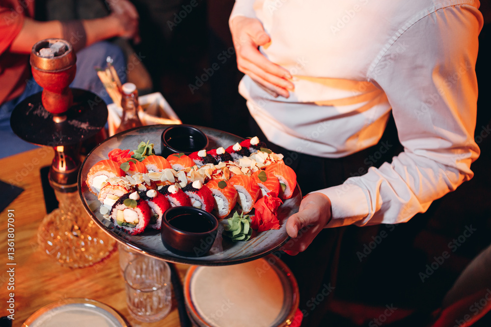 Waiter carries in his hands plate with sushi set